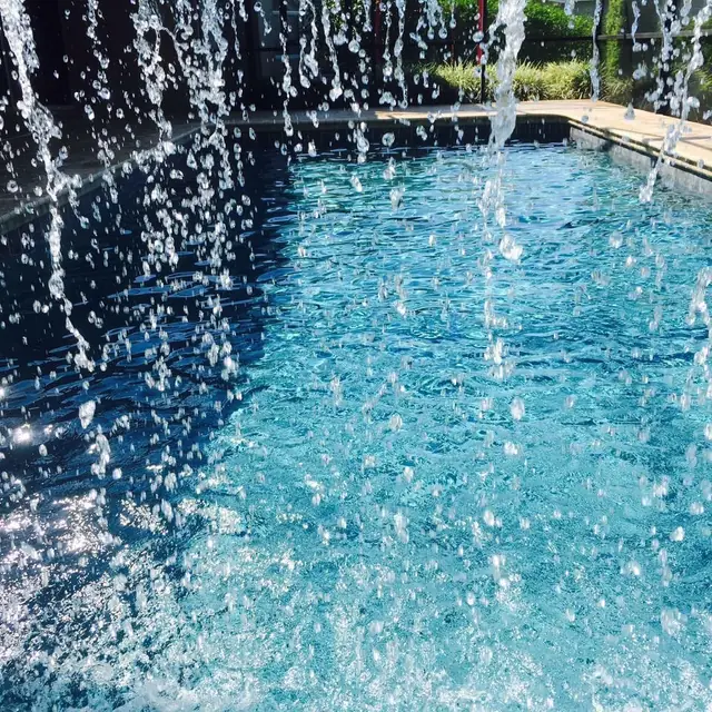 Clear blue pool water rippling under a sheer water feature