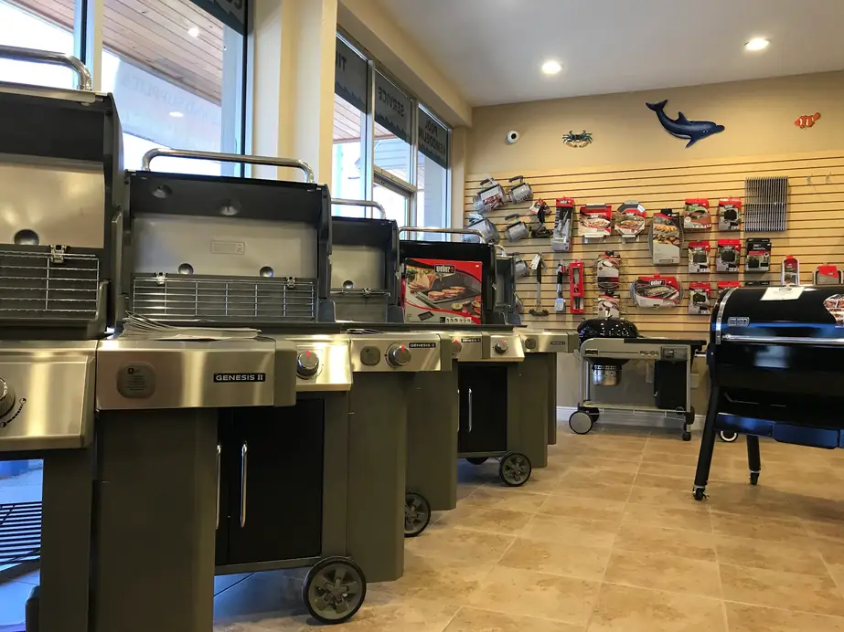 Weber gas grills lined up in the Mannix showroom beside a wall of grilling accessories